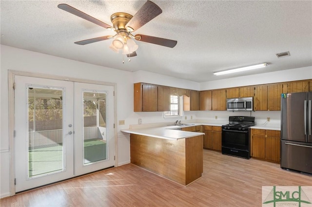 kitchen with stainless steel appliances, french doors, a textured ceiling, and kitchen peninsula