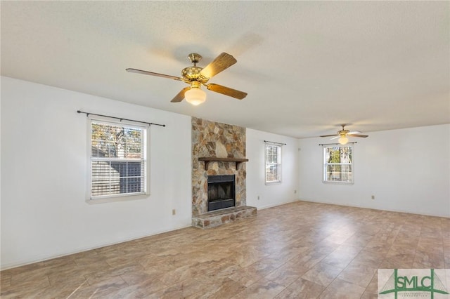 unfurnished living room with a fireplace, a textured ceiling, ceiling fan, and a healthy amount of sunlight