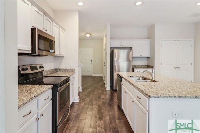 kitchen featuring stainless steel appliances, sink, white cabinetry, light stone counters, and a kitchen island with sink