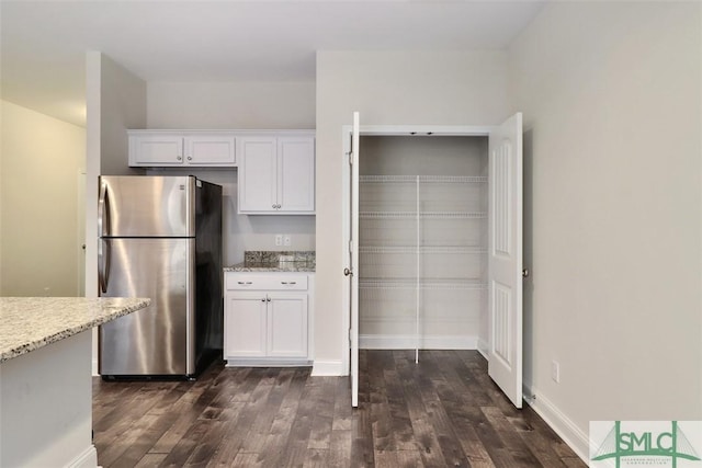 kitchen featuring stainless steel fridge, white cabinetry, light stone counters, and dark hardwood / wood-style floors