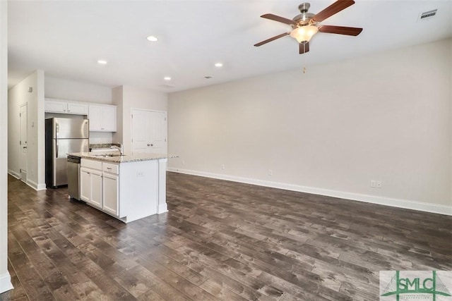 kitchen featuring a center island with sink, white cabinetry, light stone counters, and appliances with stainless steel finishes