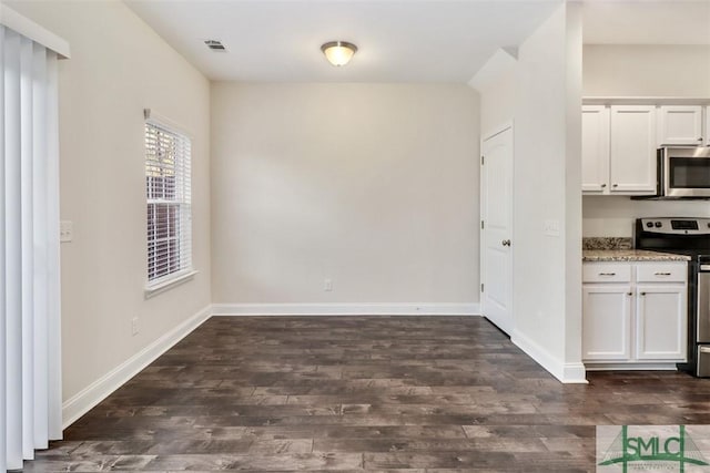 interior space with white cabinets, stainless steel appliances, light stone counters, and dark hardwood / wood-style floors