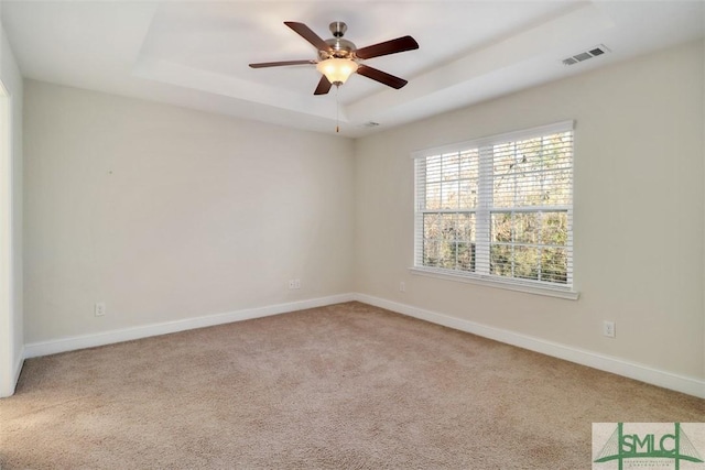 carpeted empty room featuring ceiling fan and a tray ceiling