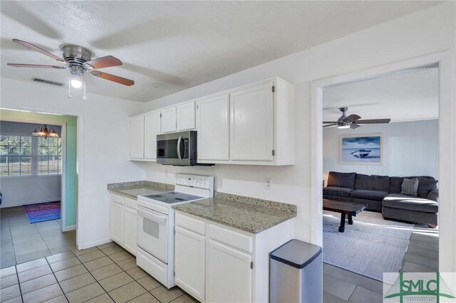 kitchen with light tile patterned floors, light stone countertops, white cabinets, and white range with electric cooktop