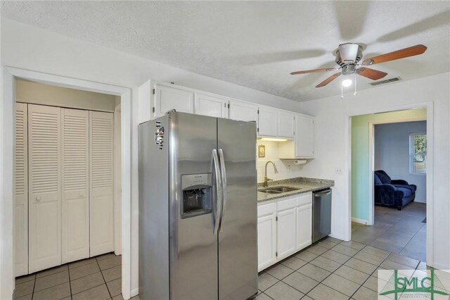 kitchen featuring sink, appliances with stainless steel finishes, white cabinetry, a textured ceiling, and light tile patterned flooring