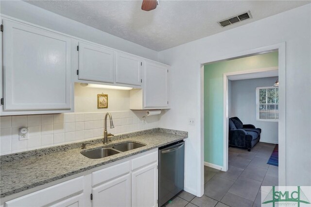 kitchen with sink, stainless steel dishwasher, white cabinets, and light stone counters