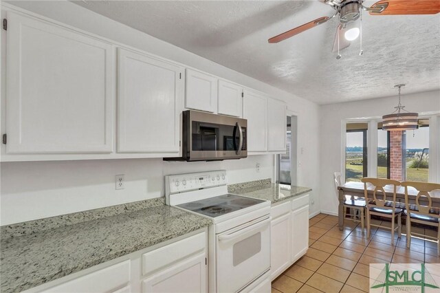 kitchen featuring light tile patterned flooring, white cabinets, light stone counters, a textured ceiling, and electric stove