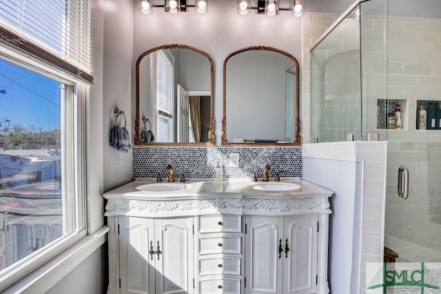 bathroom featuring a healthy amount of sunlight, a shower with door, vanity, and tasteful backsplash