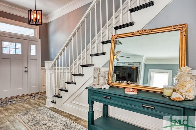 foyer with an inviting chandelier, ornamental molding, plenty of natural light, and dark wood-type flooring