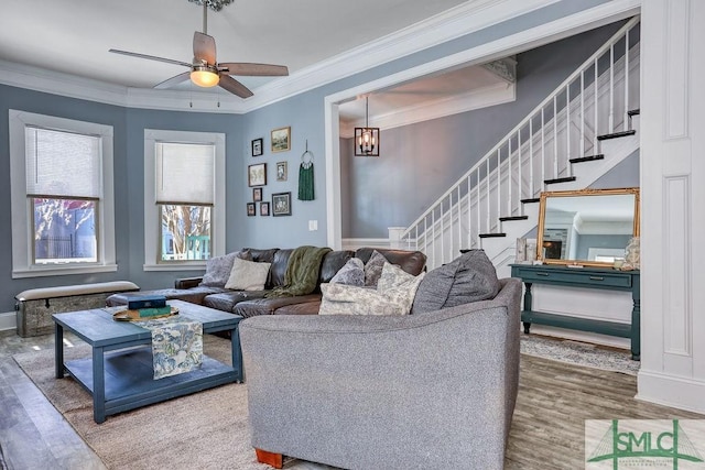 living room with ornamental molding, ceiling fan with notable chandelier, and hardwood / wood-style flooring