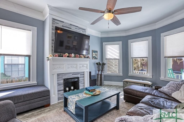 living room with ceiling fan, ornamental molding, a tile fireplace, and hardwood / wood-style flooring