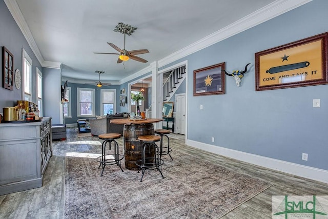 dining space with hardwood / wood-style flooring, ceiling fan, and ornamental molding