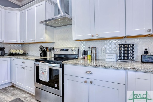 kitchen with backsplash, stainless steel electric range oven, exhaust hood, and white cabinets