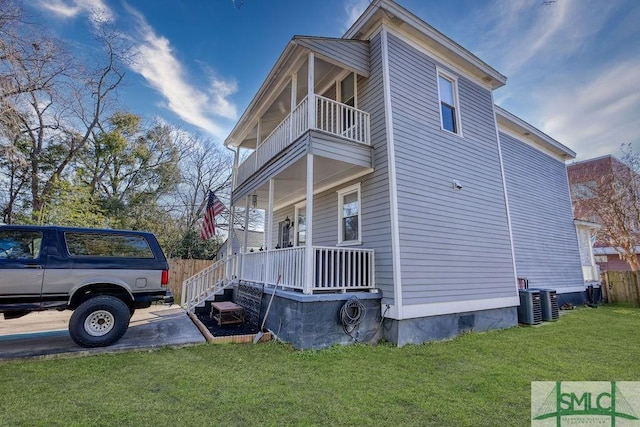 view of side of property with a porch, a balcony, and a lawn