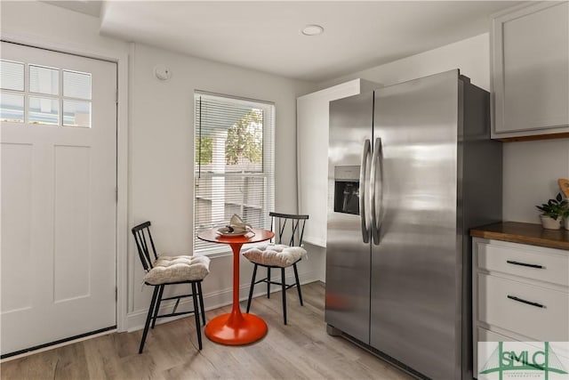 kitchen featuring light wood-type flooring, stainless steel refrigerator with ice dispenser, and white cabinetry