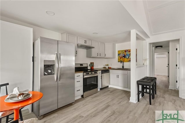 kitchen with a wall unit AC, white cabinetry, light wood-type flooring, and appliances with stainless steel finishes