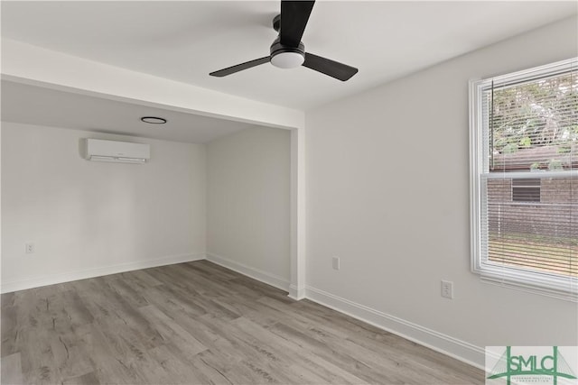 spare room with ceiling fan, a wall mounted AC, and light wood-type flooring