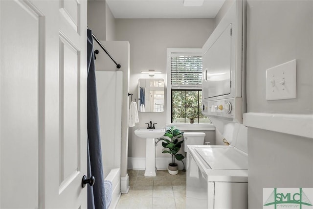 full bathroom featuring stacked washer / dryer, toilet, tile patterned floors, sink, and shower / bathtub combination