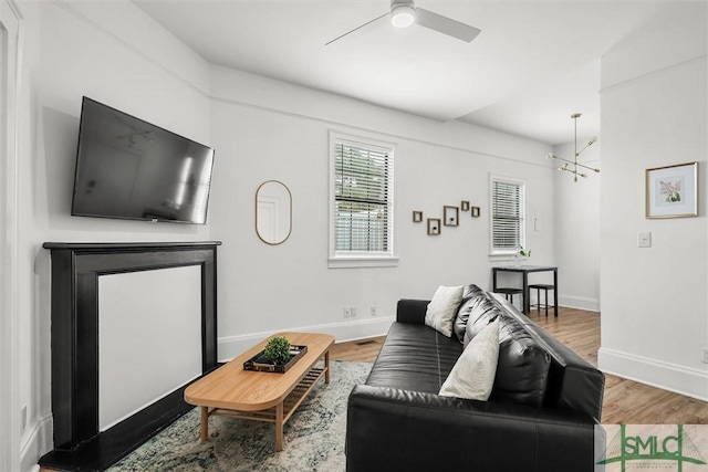 living room with ceiling fan with notable chandelier and wood-type flooring