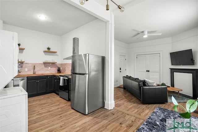 kitchen with wooden counters, stainless steel appliances, sink, light hardwood / wood-style flooring, and tasteful backsplash