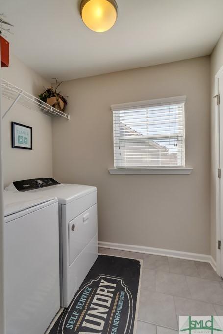 laundry room with washing machine and clothes dryer and light tile patterned floors