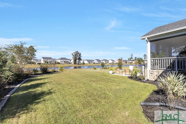 view of yard with a sunroom and a water view