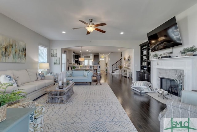 living room featuring a tiled fireplace, ceiling fan, and hardwood / wood-style flooring