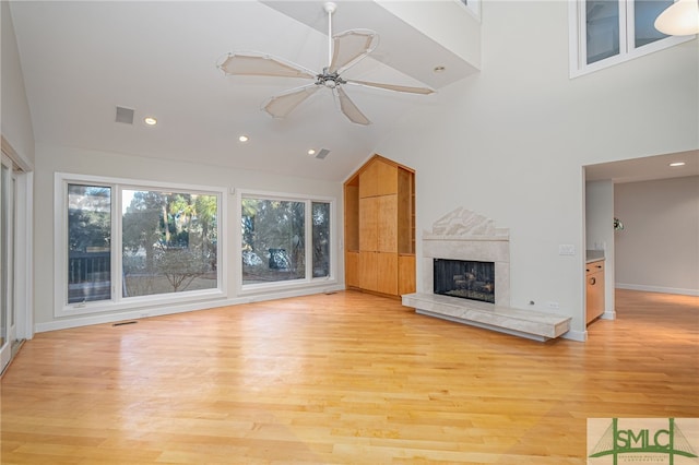 unfurnished living room featuring ceiling fan, high vaulted ceiling, a fireplace, and light hardwood / wood-style floors