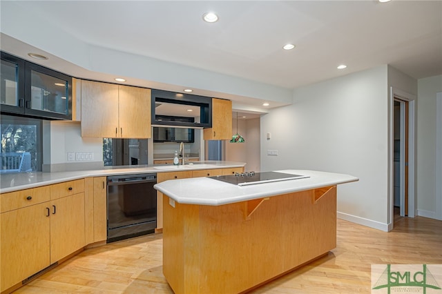 kitchen featuring black appliances, a kitchen island, a kitchen bar, light brown cabinetry, and light wood-type flooring