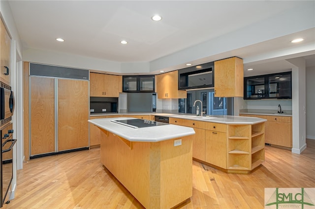 kitchen with a kitchen island, sink, light hardwood / wood-style floors, and black appliances