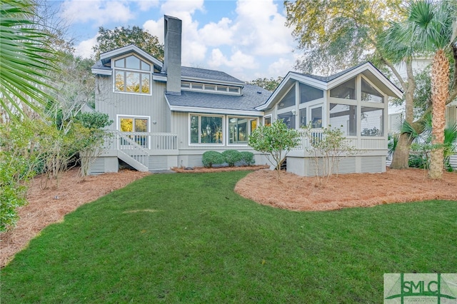 back of house featuring a deck, a sunroom, and a lawn