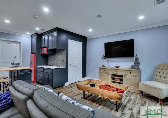 living room with hardwood / wood-style flooring, crown molding, and sink