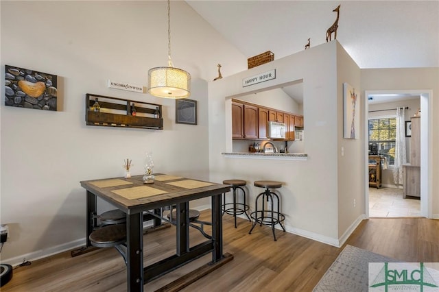 dining area featuring sink, lofted ceiling, and hardwood / wood-style flooring