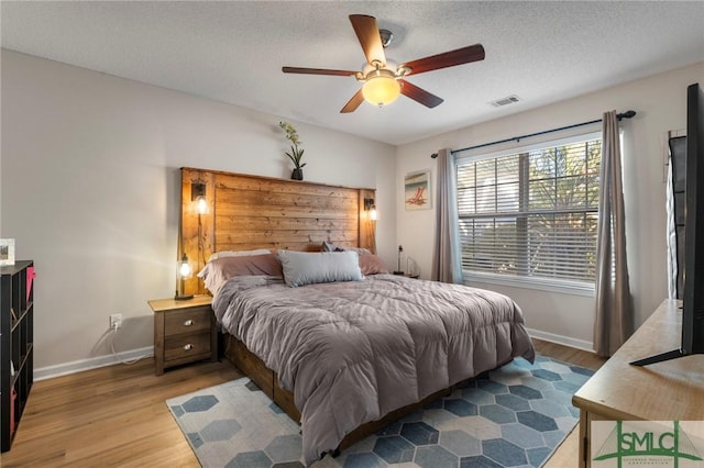 bedroom with ceiling fan, hardwood / wood-style floors, and a textured ceiling