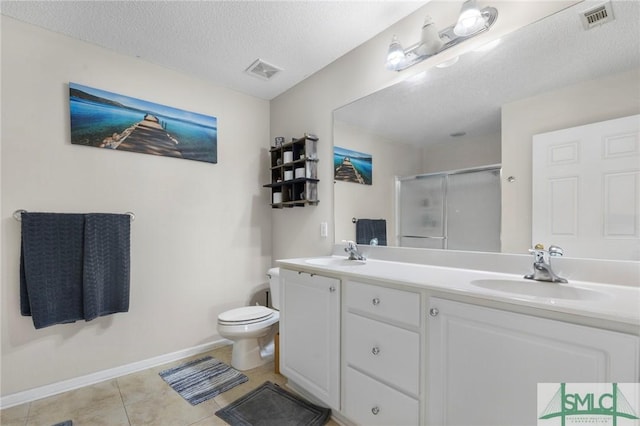 bathroom with a textured ceiling, tile patterned flooring, toilet, a shower with door, and vanity