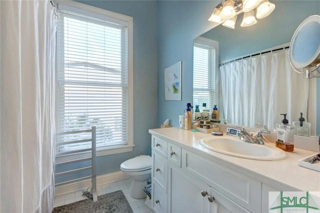 bathroom with a healthy amount of sunlight, vanity, tile patterned floors, and toilet