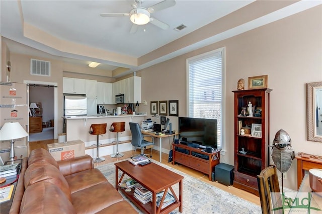 living room featuring ceiling fan and a tray ceiling