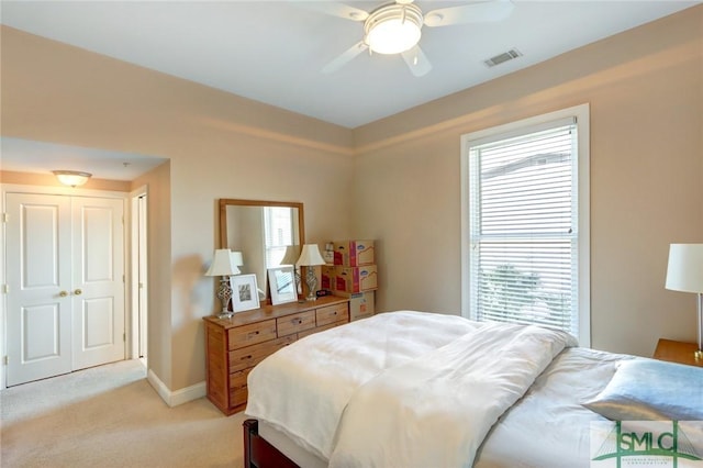 bedroom with light colored carpet, ceiling fan, a closet, and multiple windows