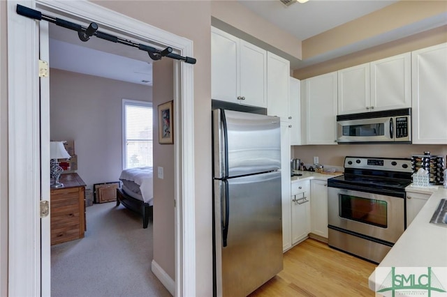 kitchen featuring appliances with stainless steel finishes, light hardwood / wood-style flooring, and white cabinets