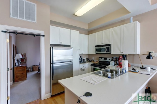 kitchen featuring white cabinetry, kitchen peninsula, and appliances with stainless steel finishes