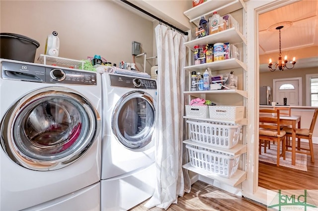 laundry area with an inviting chandelier, washing machine and dryer, and wood-type flooring