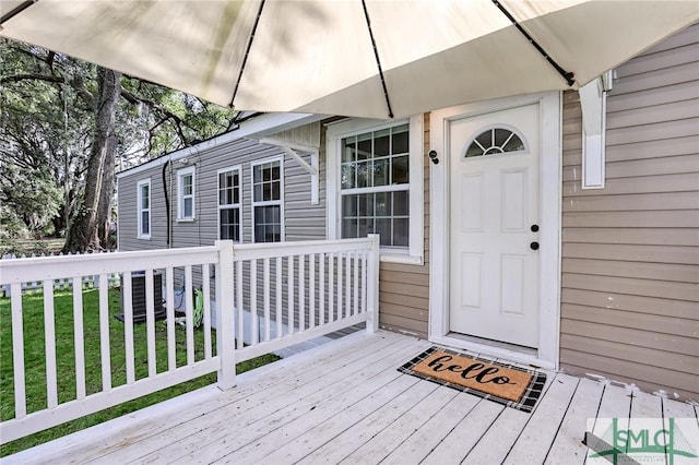 view of exterior entry featuring a wooden deck and a lawn