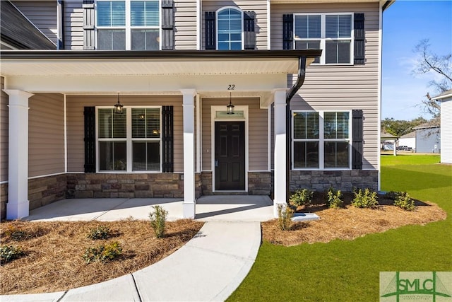 doorway to property with stone siding and a porch