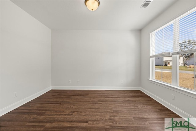 unfurnished room featuring baseboards, visible vents, and dark wood-style flooring