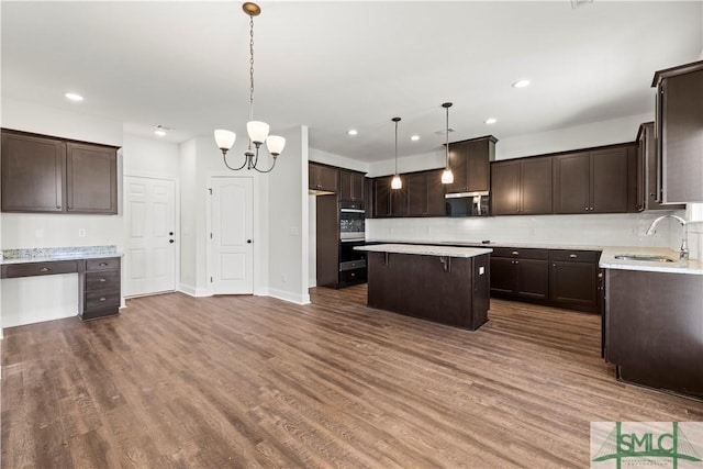 kitchen featuring dark brown cabinetry, a center island, dark wood-style flooring, and a sink