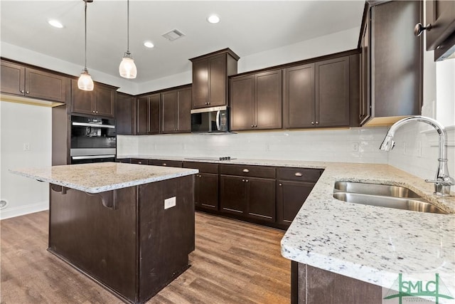 kitchen with visible vents, dark brown cabinets, stainless steel microwave, double wall oven, and a sink