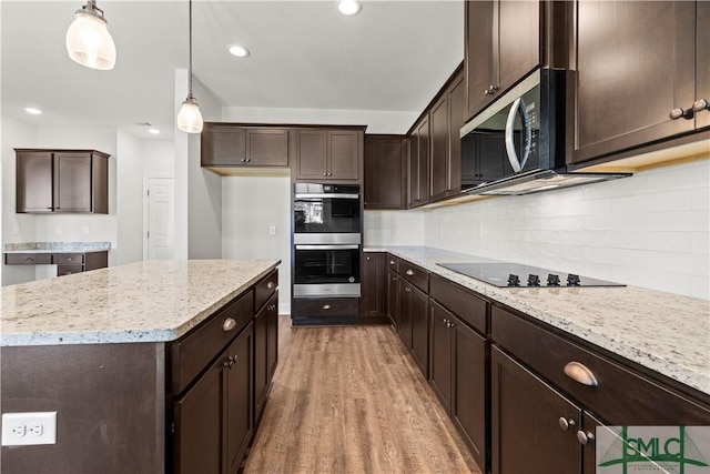 kitchen featuring stainless steel double oven, light wood-style floors, dark brown cabinetry, decorative backsplash, and black electric stovetop