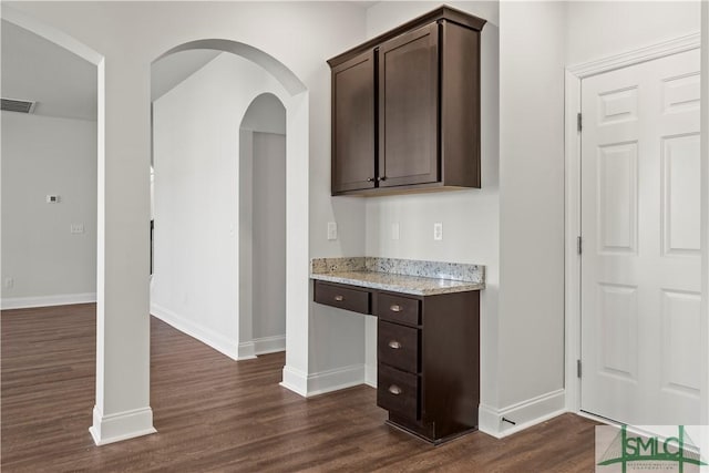 bar featuring visible vents, baseboards, dark wood-type flooring, and arched walkways