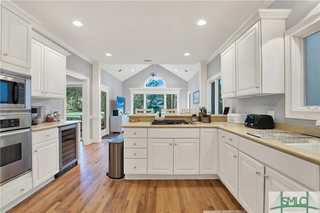 kitchen with appliances with stainless steel finishes, white cabinetry, and wine cooler