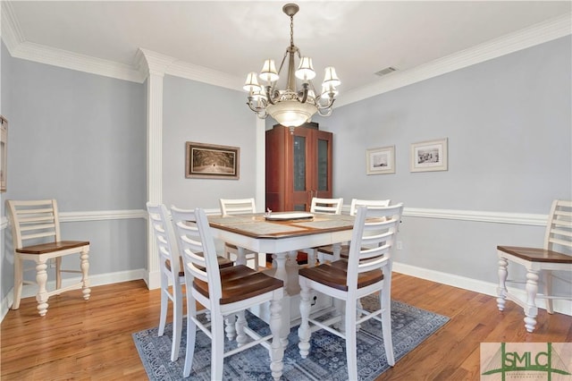 dining room with ornamental molding, an inviting chandelier, and light hardwood / wood-style floors